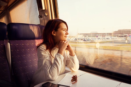 46324670 - young woman traveling looking out the window while sitting in the train.